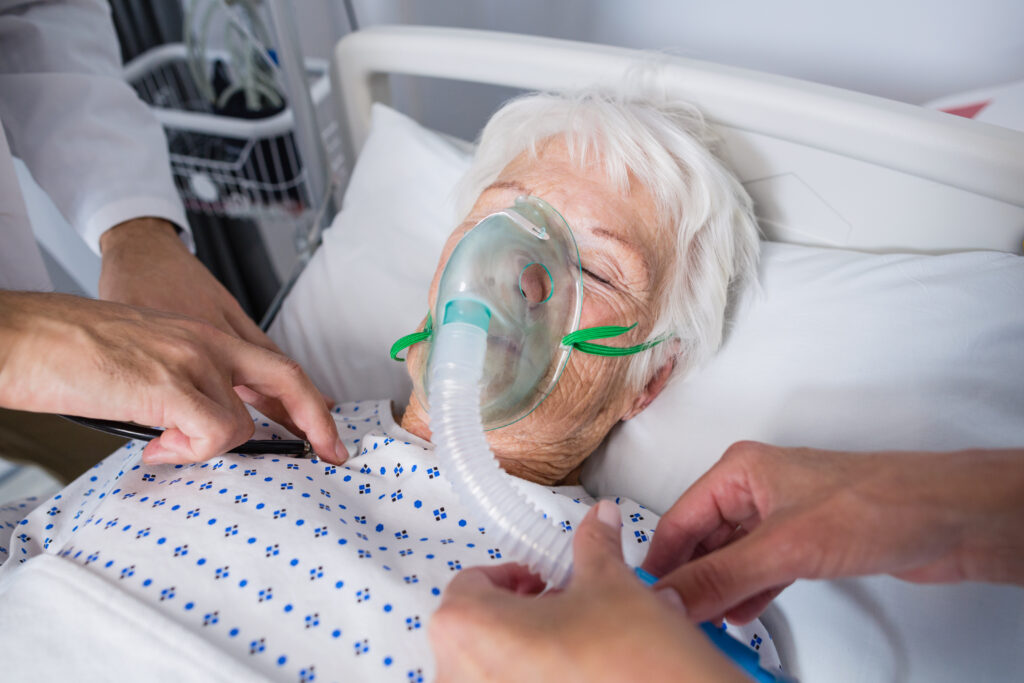 doctors examining senior patient with stethoscope in hospital bed
